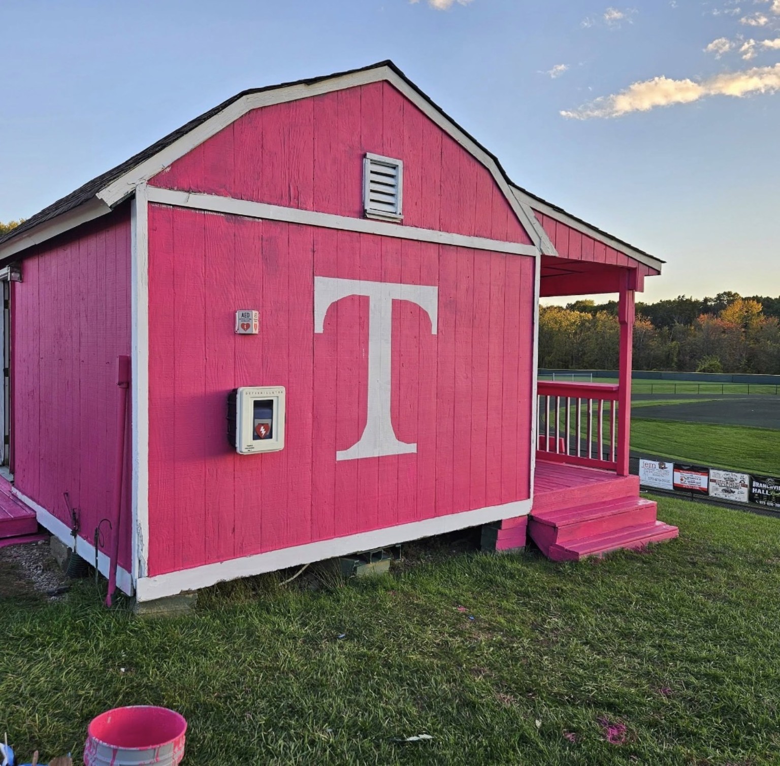 After: the same building painted bright magenta with a large white T
